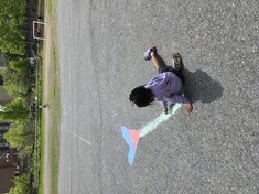 Girls draws on asphalt with colourful chalk